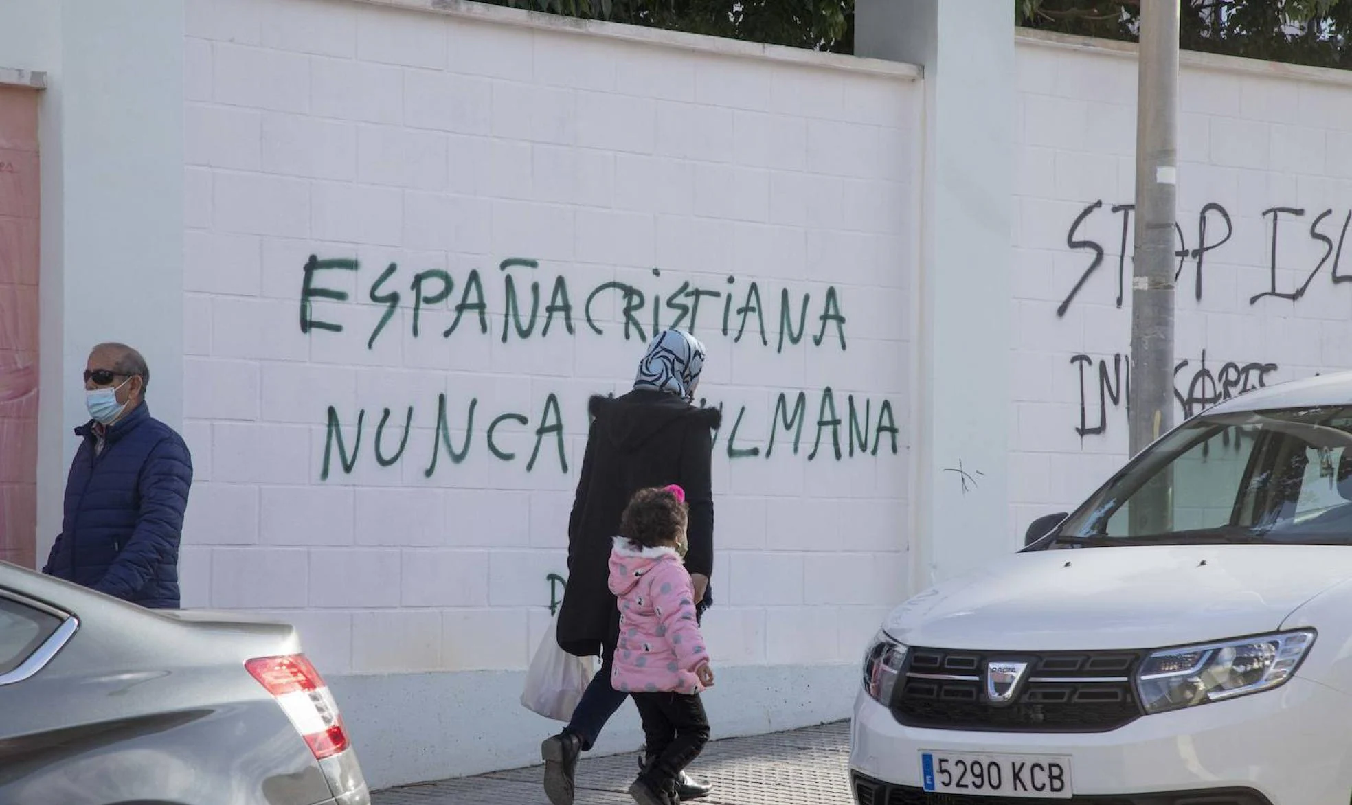 Una mujer y una niña pasan frente a las pintadas ofensivas al Islam en una pared del Club Santiago. 