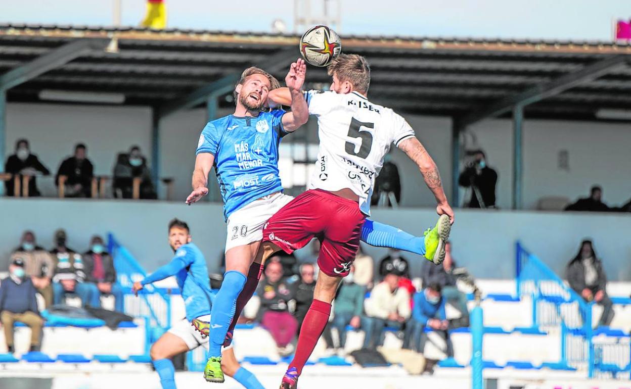 El visitante Kaiser le mete el codo al delantero local Titi en un salto, en El Rubial