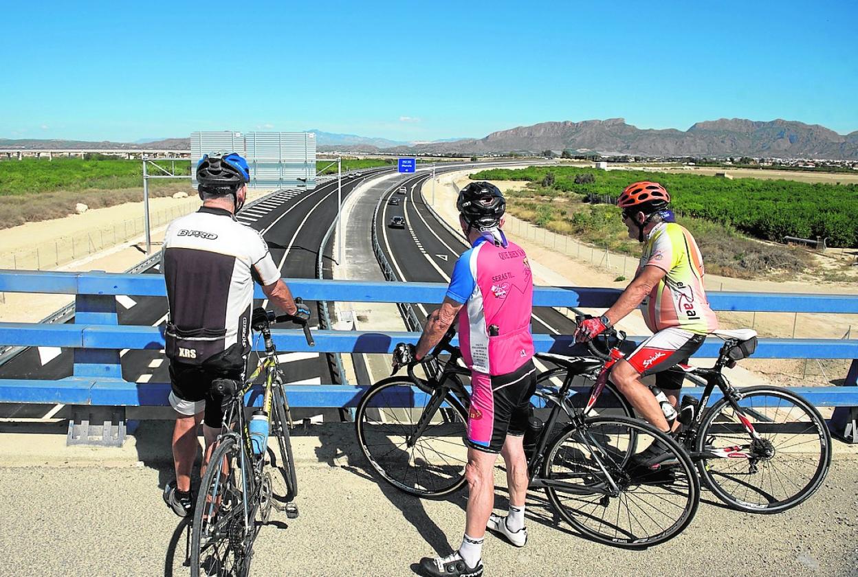 Unos ciclistas observan el enlace del vial del Reguerón con la 'autovía del bancal', con Santomera al fondo. 