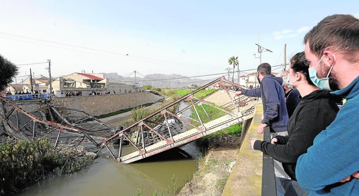 Vecinos afectados por el derrumbe del puente entre El Raal y Beniel contemplaban a finales de marzo el estado del vehículo y de la pasarela. 