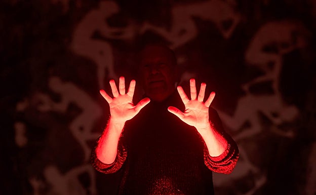 Las manos de Tomy Ceballos con el resplandor del color rojo de laboratorio. 