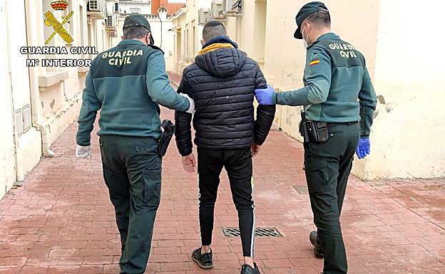 Dos agentes con uno de los detenidos.