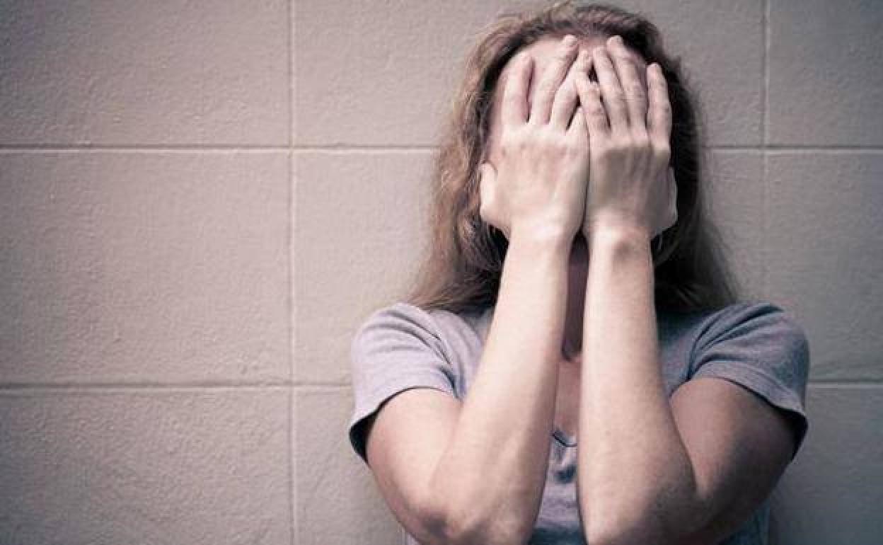 Una mujer con depresión se cubre el rostro.