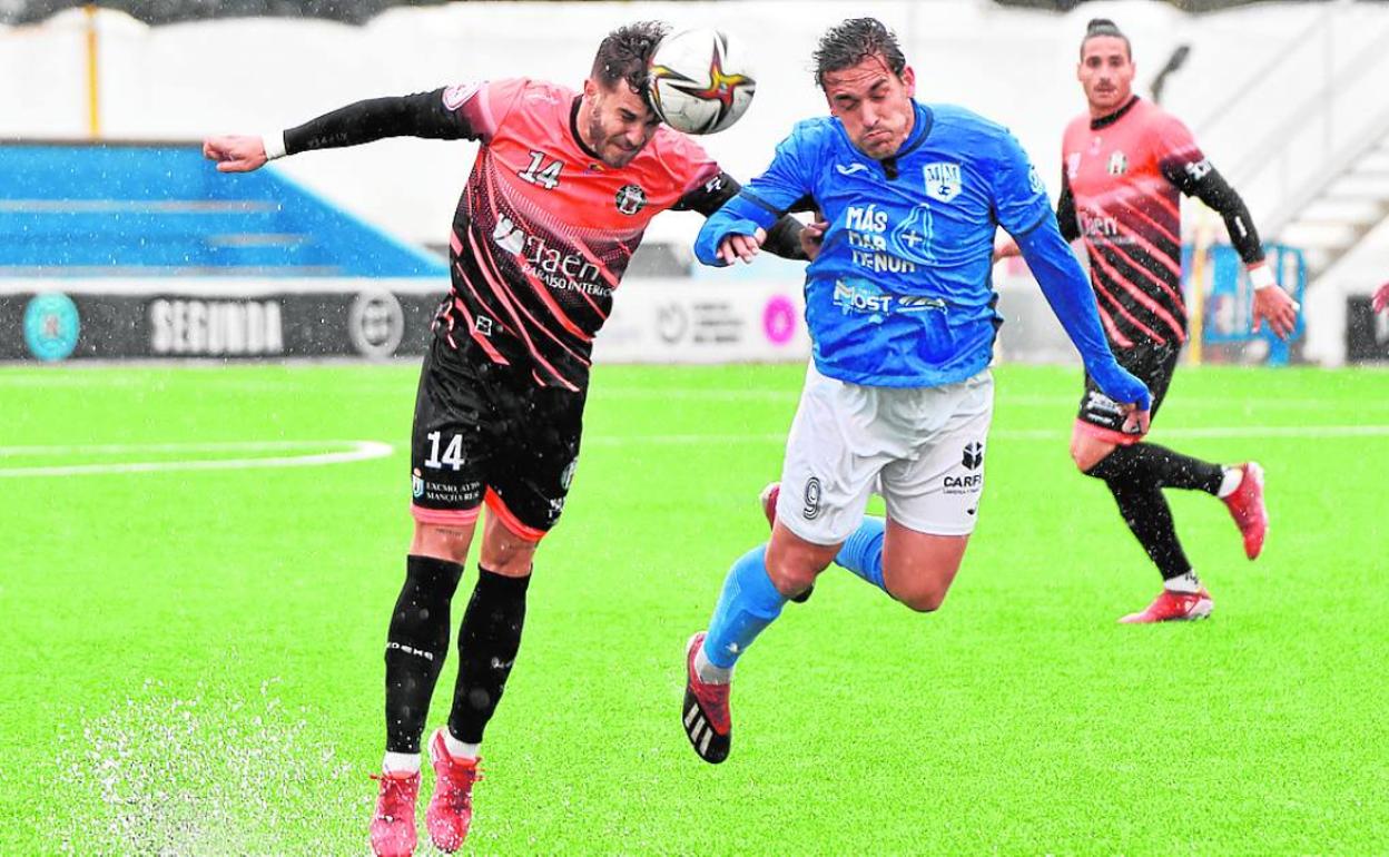 Mauro, del Mancha Real, despeja ante el goleador local Edu Ubis, ayer en El Pitín.