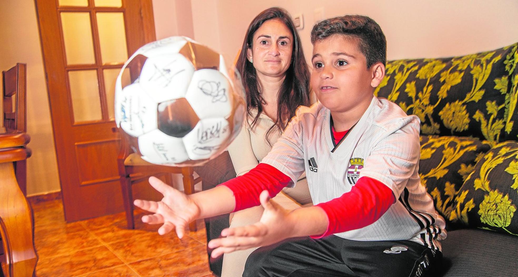 Alejandro, junto a su madre Natalia, juega con la pelota que le firmaron los jugadores del Efesé. 