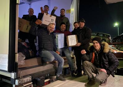 Imagen secundaria 1 - A la izquierda, el coordinador de la ONG para la entrega de la ayuda, Yuriy Voytsitsky (con guantes blancos), junto a siete compañeros, en la descarga del tráiler en Medyka; a la derecha, uno de los voluntarios muestra feliz una de las cajas con su bandera.