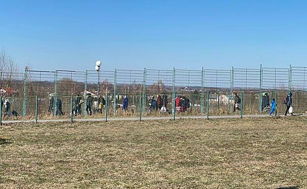 Decenas de refugiados ucranianos recorren a pie los últimos metros hasta la frontera para acceder a Polonia cargados con sus pertenencias, expulsados por los ataques del Ejército ruso en su país, este viernes, frente al área donde descarga el camión murciano.