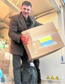 Imagen secundaria 2 - A la izquierda, el coordinador de la ONG para la entrega de la ayuda, Yuriy Voytsitsky (con guantes blancos), junto a siete compañeros, en la descarga del tráiler en Medyka; a la derecha, uno de los voluntarios muestra feliz una de las cajas con su bandera.