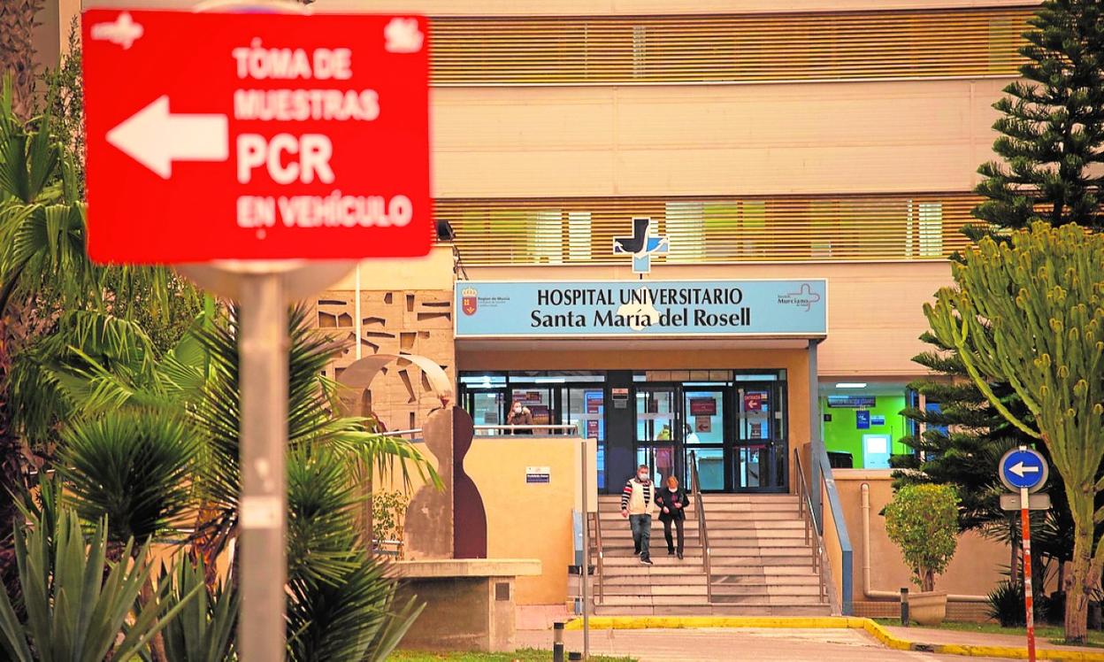 Dos personas salen del Hospital Santa María del Rosell, donde hay carteles sobre la Covid, ayer. 