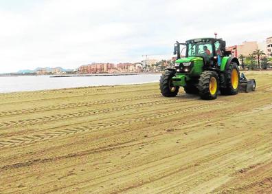Imagen secundaria 1 - Arriba, operarios rehabilitan la arena de una playa de Lo Pagán, este viernes; a la izquierda, un tractor iguala la arena de una playa de Águilas; y, a la derecha, un ciclista pasea junto al Mar Menor, en Playa Paraíso.
