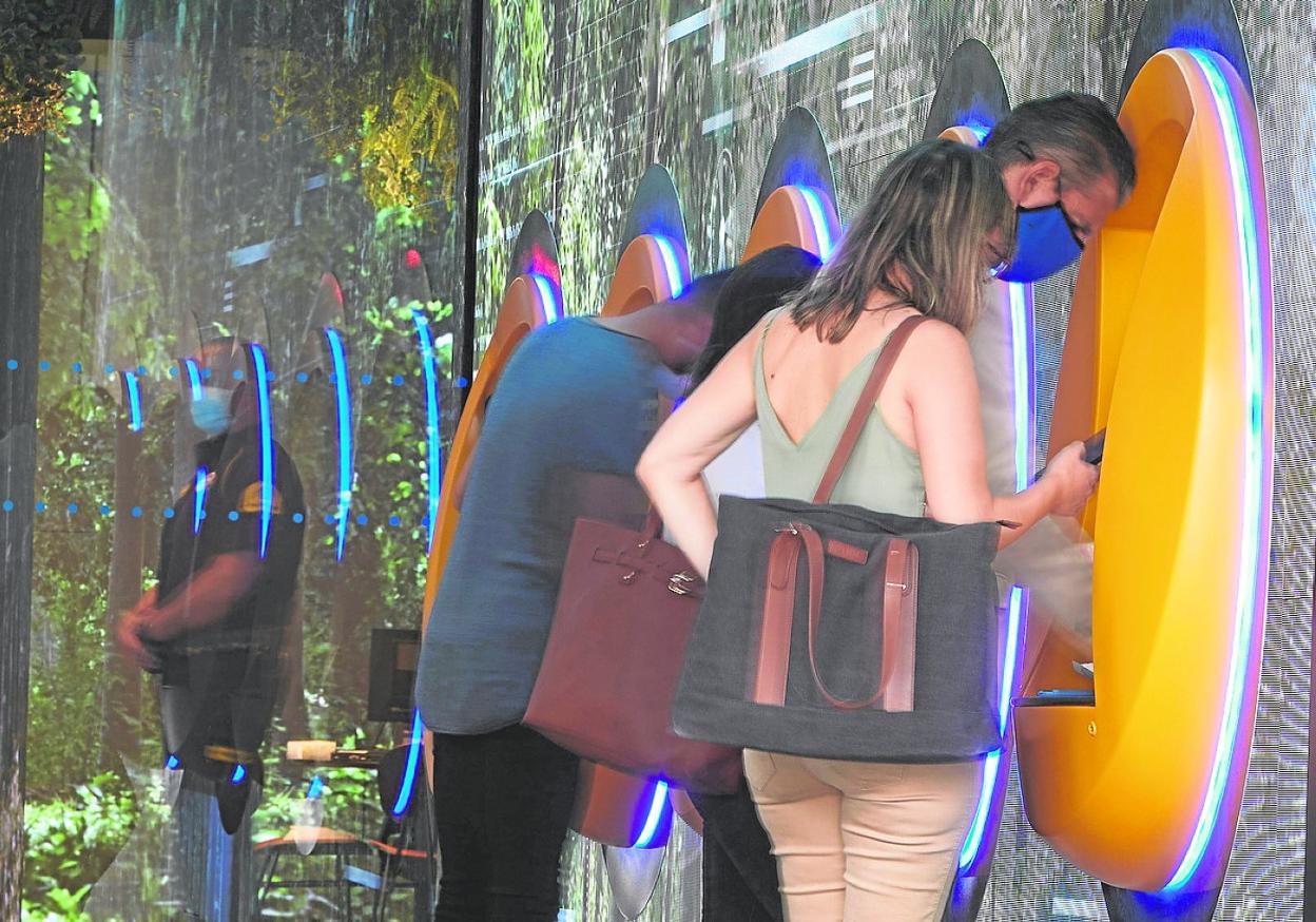 Clientes sacando dinero de cajeros automáticos. 