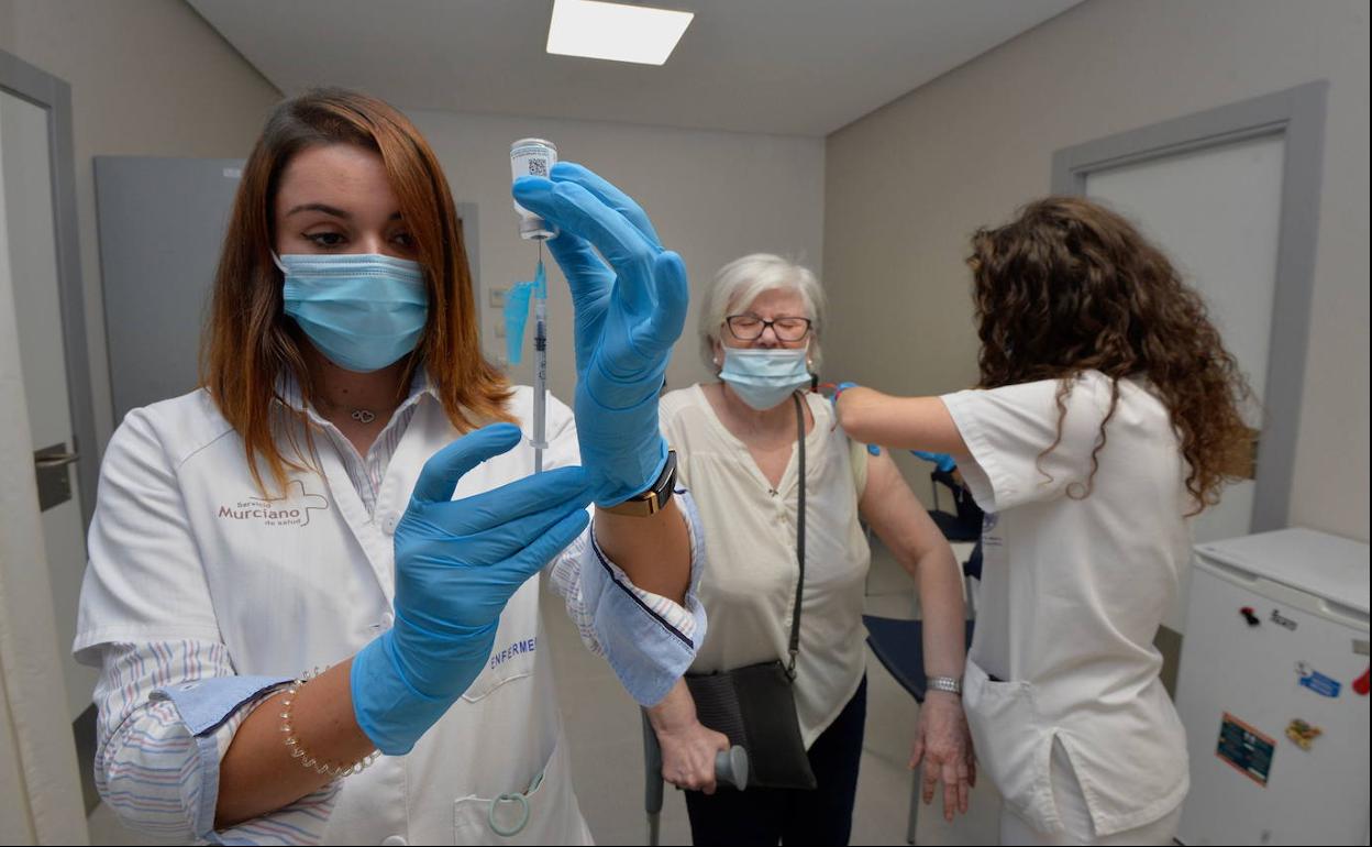 Dos sanitarias administran simultáneamente las vacunas de la gripe y la Covid a una paciente, el pasado otoño en Murcia.
