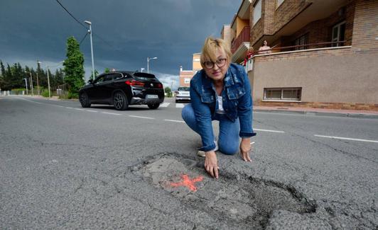 Mari Carmen Ruiz muestra uno de los baches que presenta la calzada en la calle Juan XXIII de Cabezo de Torres.