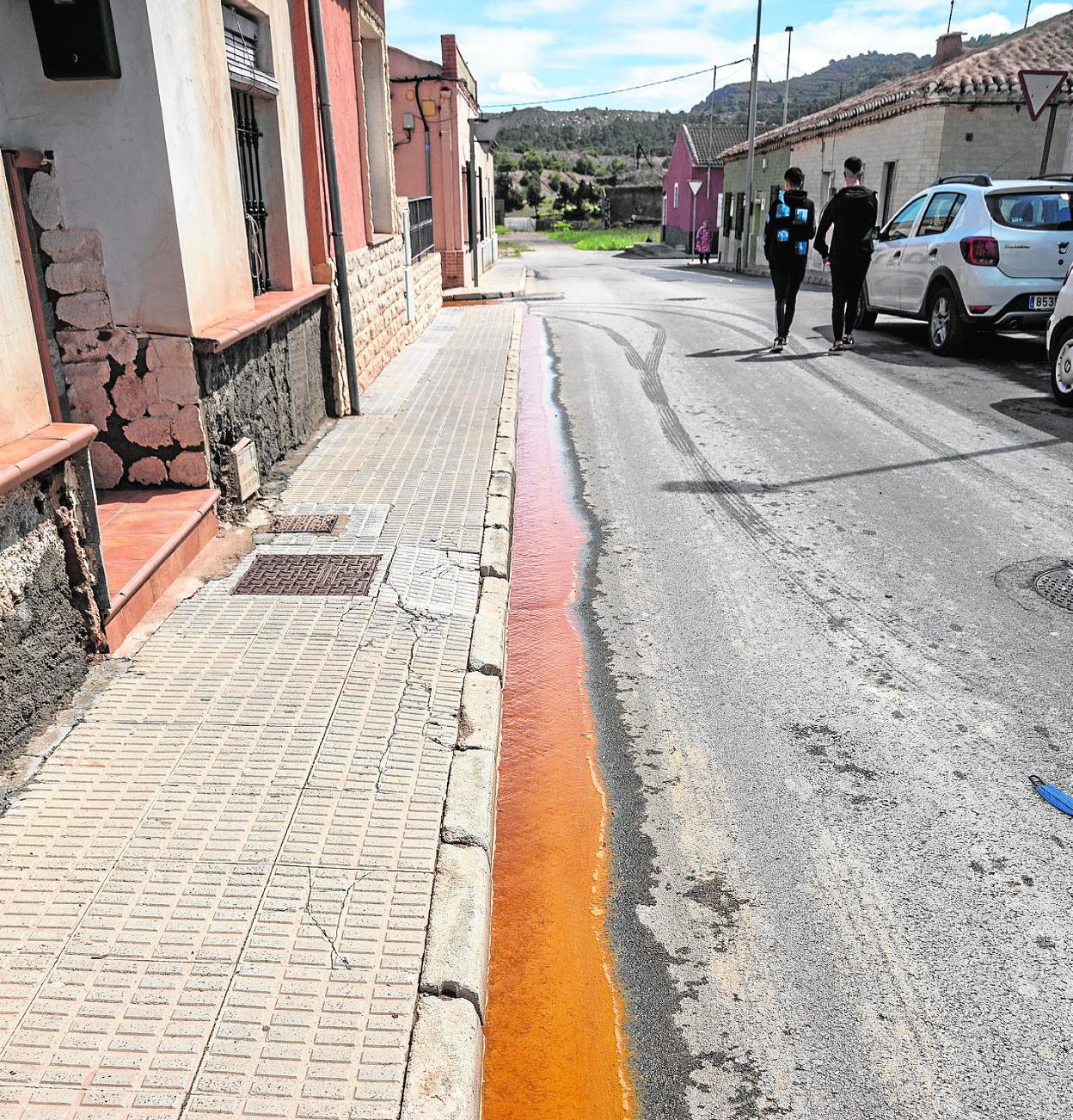 Dos chicos caminan por una calle de Llano del Beal, junto a un vertido minero, en abril. 