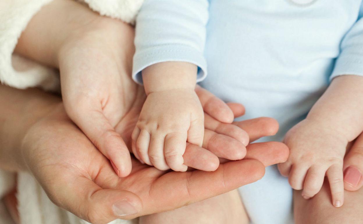 Unos padres sujetan la mano de su hijo recién nacido, en una fotografía de archivo.