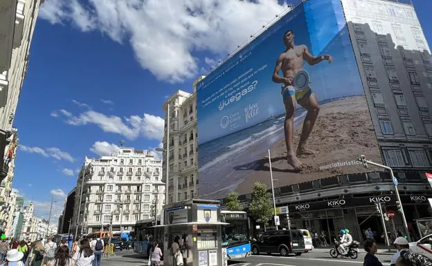 Viandantes en la Gran Vía madrileña, ayer, junto al cartel gigante con la campaña publicitaria que protagoniza Alcaraz.