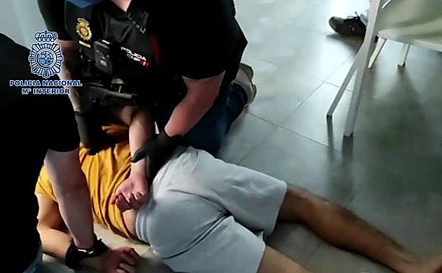 Dos agentes inmobilizan a uno de los arrestados.