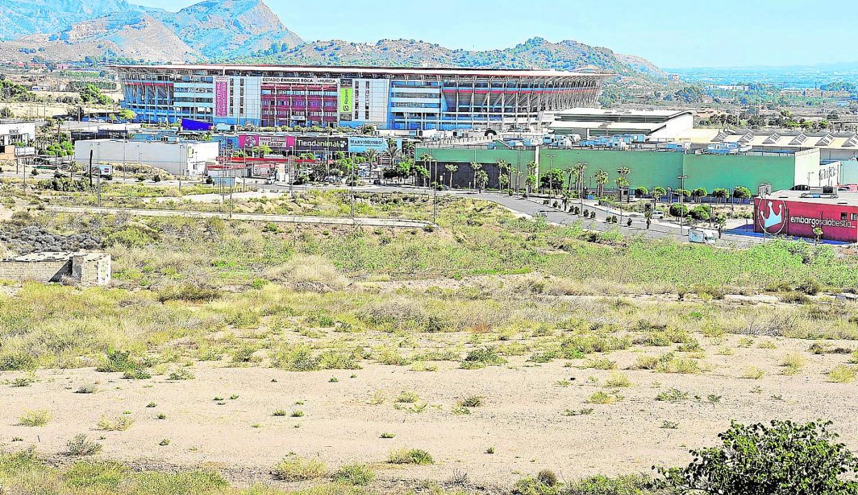 En primer plano, parte de los terrenos donde iría asentada la nueva ciudad deportiva grana. Al fondo, el estadio Enrique Roca. 