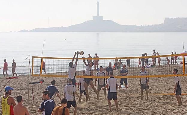 Partido de voley-playa, con el faro de Cabo de Palos al fondo, en La Manga.