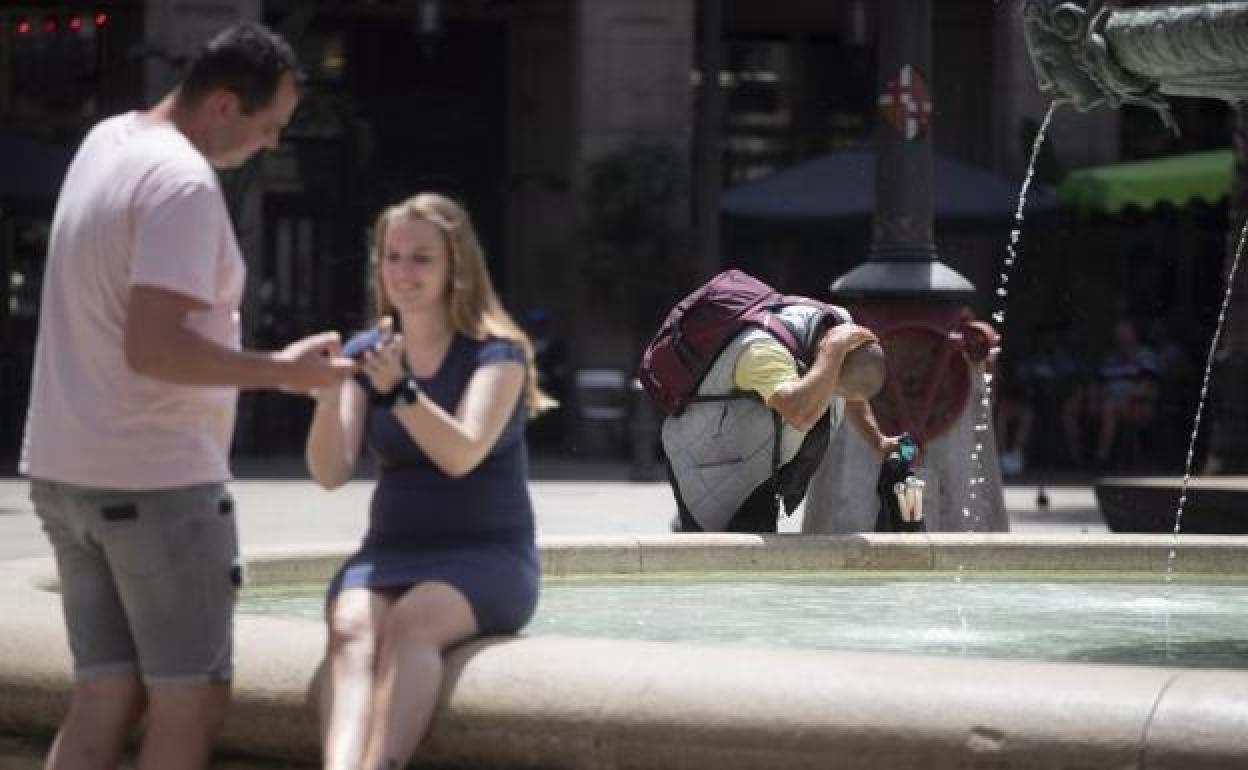 Un hombre se refresca en una fuente. 