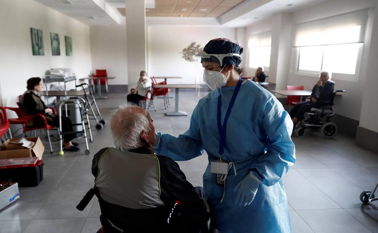 Una trabajadora de una residencia hace un test de antígenos a un anciano. 