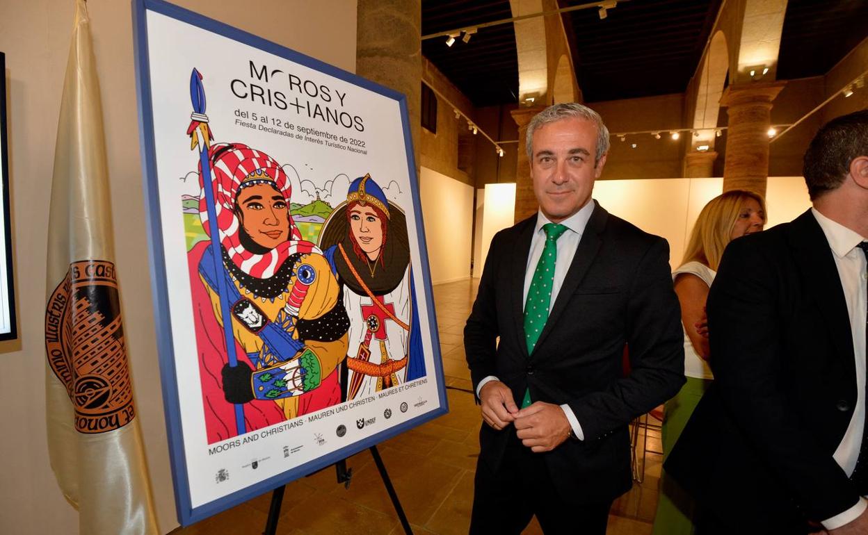 El periodista Antonio Peñarrubia, ayer, junto al cartel anunciador de Moros y Cristianos. 