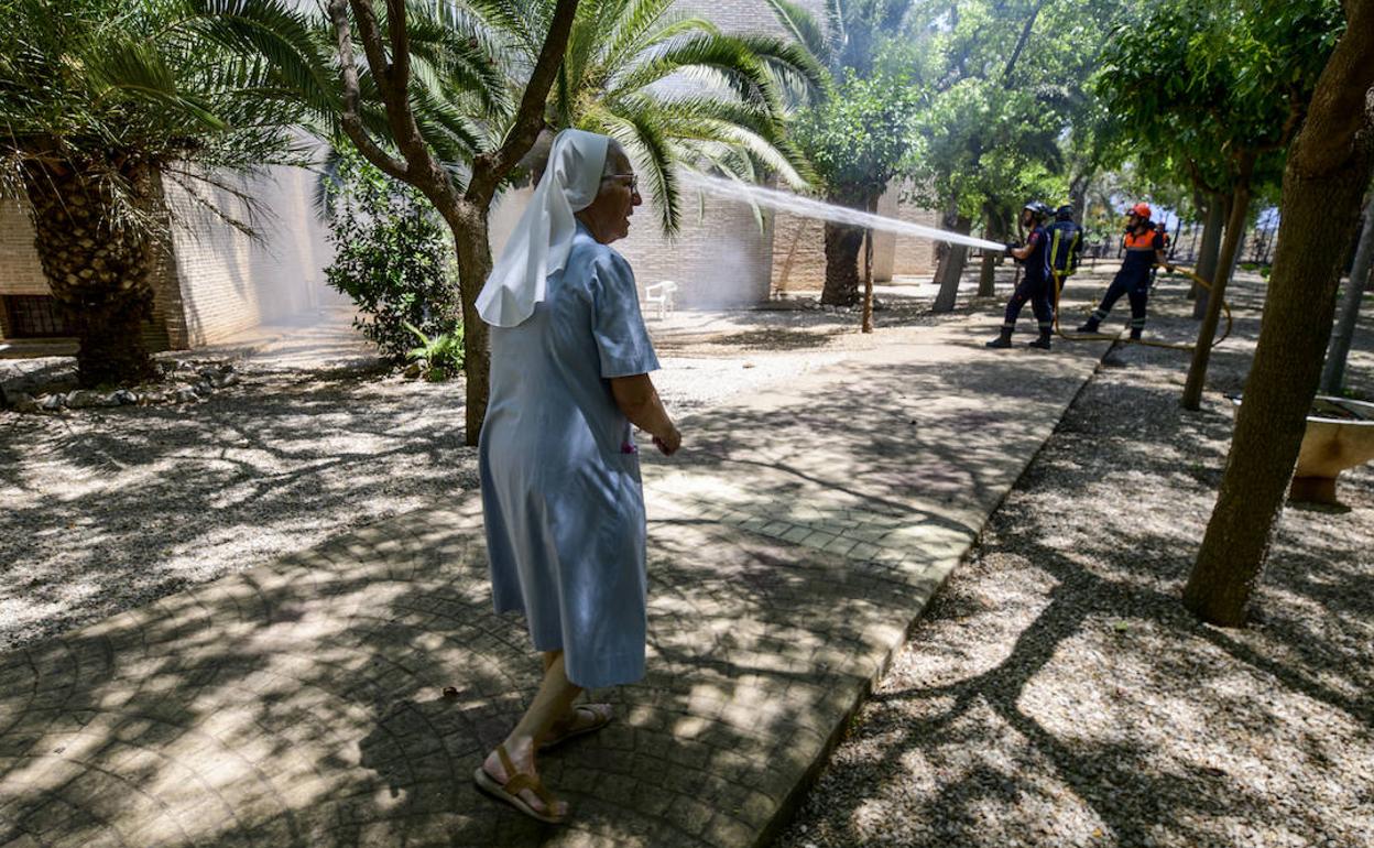 Una monja, junto dos bomberos que apagan las llamas en el incendio originado este viernes en Guadalupe.