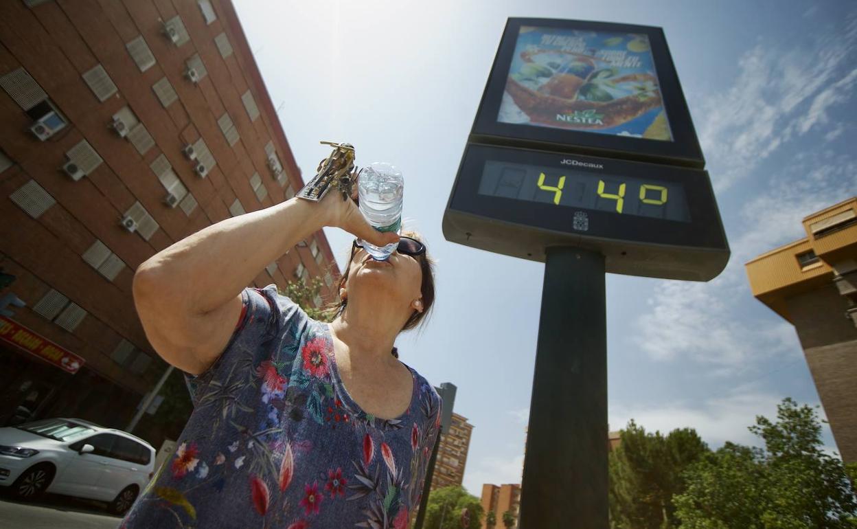 Una vecina de Murcia se refresca bajo uno de los termómetros de la ciudad.