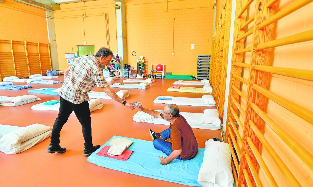 Un hombre recibe una botella de agua de uno de los voluntarios, en el Palacio de los Deportes de Murcia, el pasado lunes. 