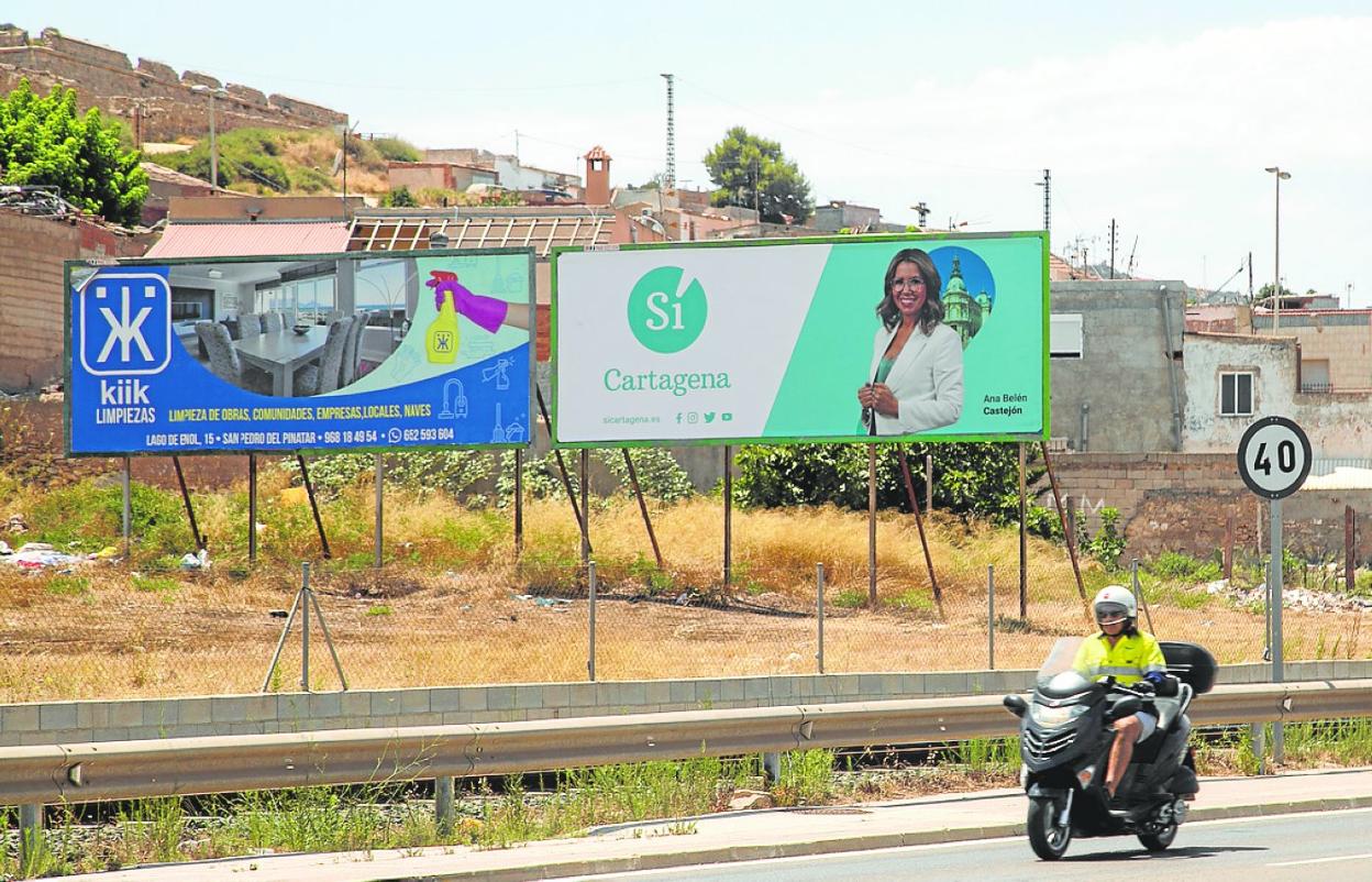 Un motorista pasa ante un cartel con la imagen de Ana Belén Castejón, en Los Mateos. 