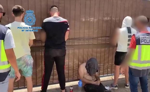 Dos agentes escoltan a los detenidos en la operación. 