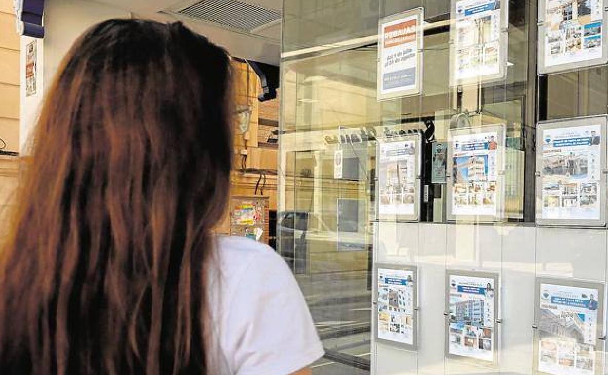 Una mujer observa la oferta de vivienas en alquiler en el escaparate de una oficina inmobiliaria en Murcia, en una imagen de archivo.