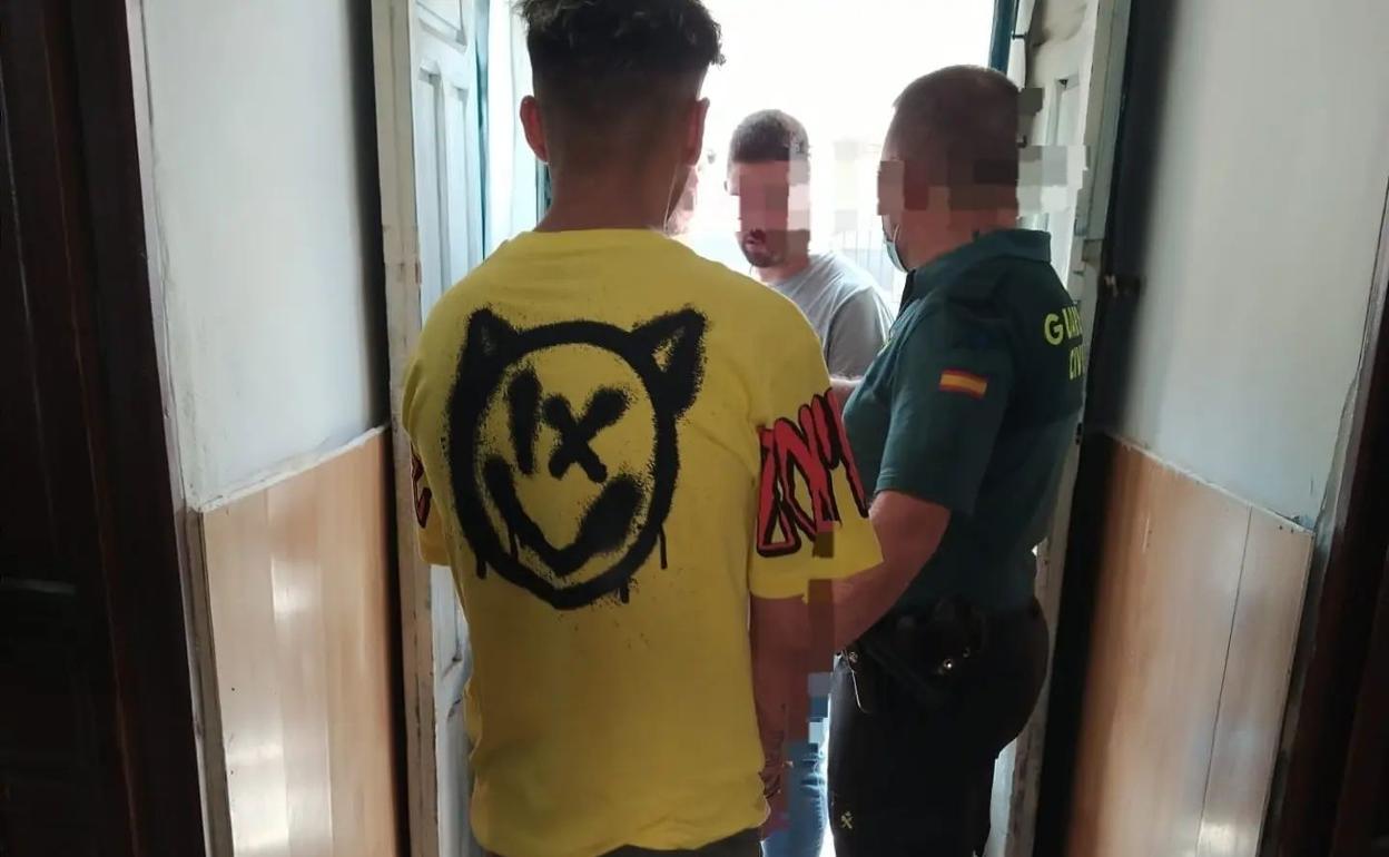 Un guardia civil traslada al arrestado tras el registro de su domicilio.