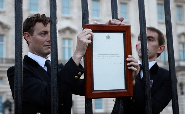 Personal del palacio de Buckingham cuelga un mensaje anunciando la muerte de la reina