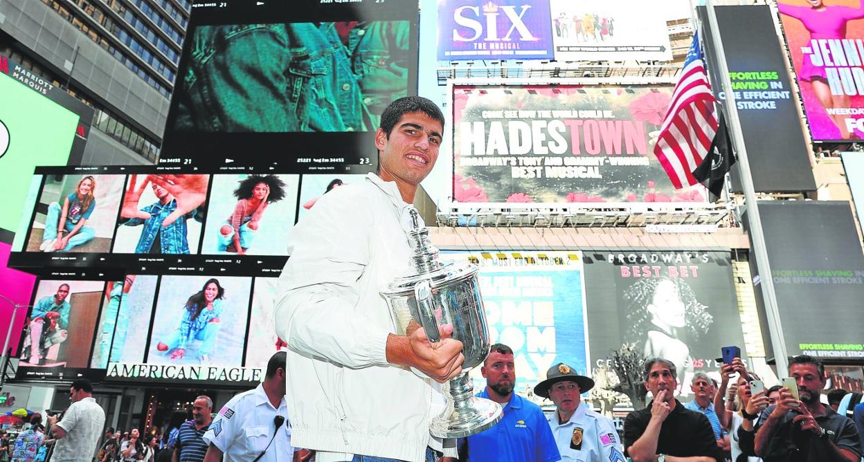 Carlos Alcaraz posa con su copa de campeón en Times Square, ayer, antes de regresar a España. 