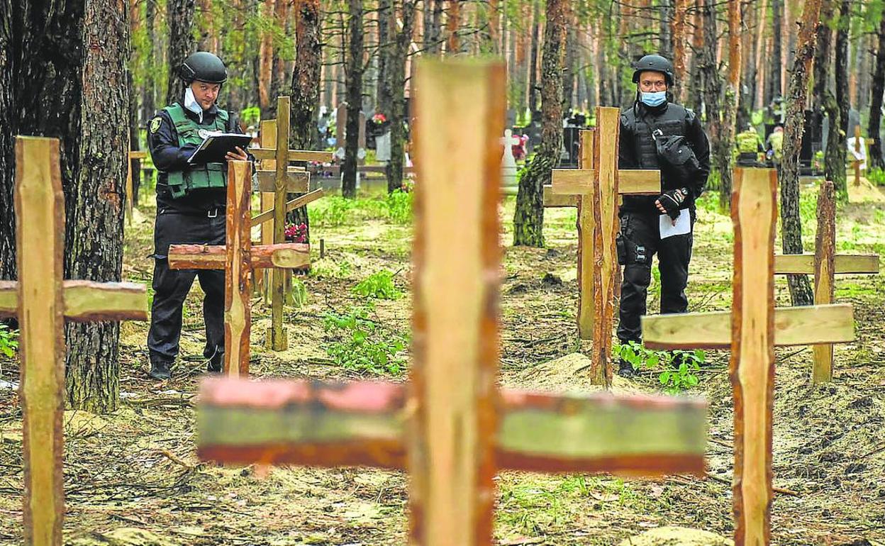 Dos policías analizan la fosa común descubierta en Izium, en la región de Járkov. 