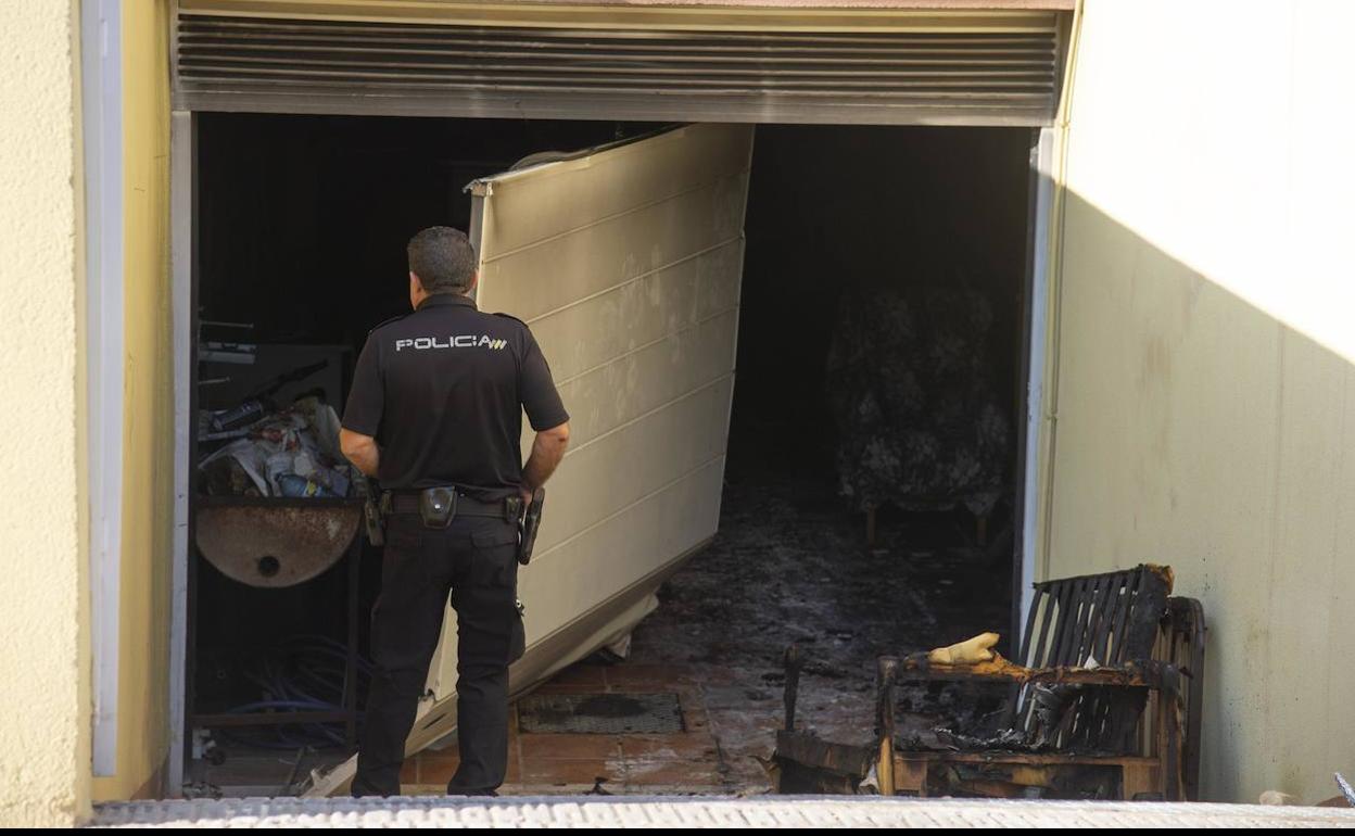 Un agente de la Policía inspecciona el garaje en el que se ha originado el incendio.
