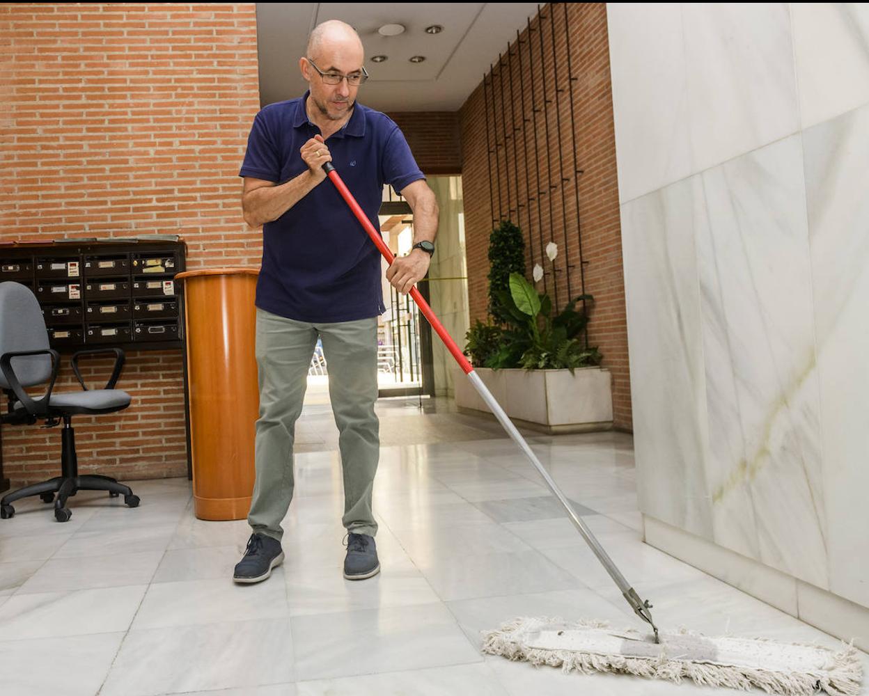 Francisco José Egea pasa la mopa en la entrada del edificio del centro de Murcia donde trabaja como conserje. 