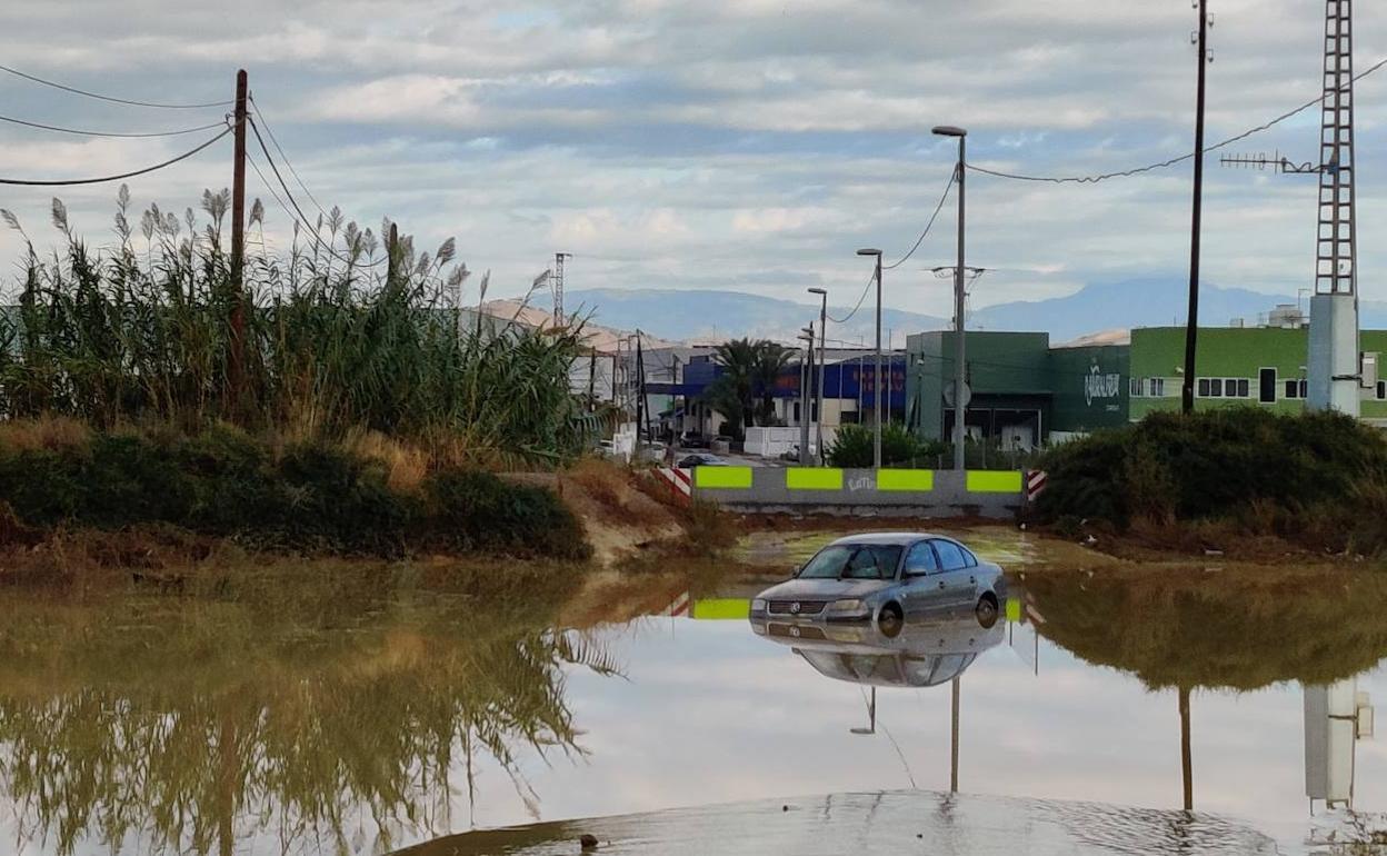 Un vehículo queda atrapado en una rambla tras subir el nivel del agua por las intensas lluvias de la madrugada de este lunes. 