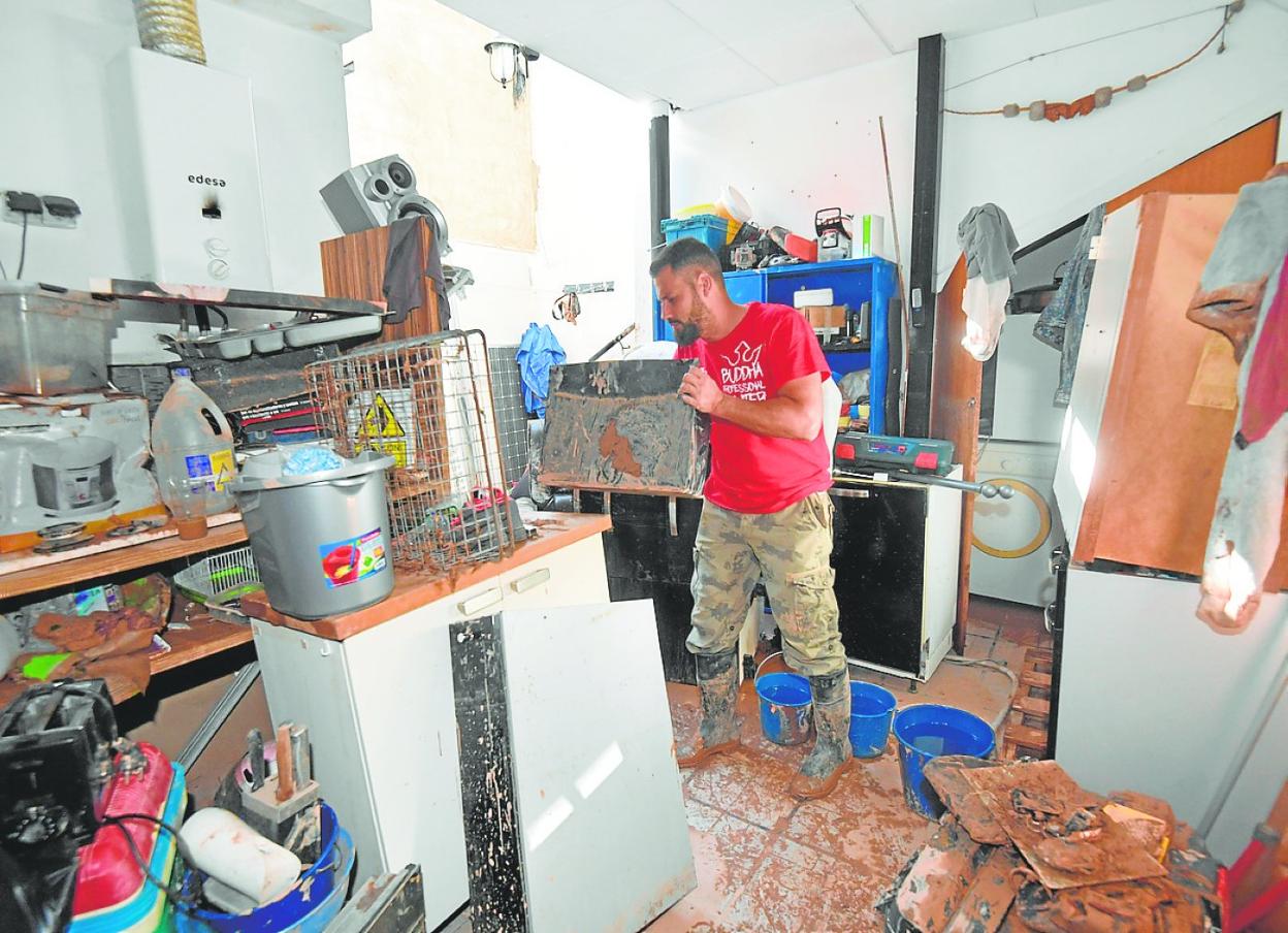 Ginés Tormo retira algunos de sus bienes del patio por el que se accede a la terraza en la que se refugió del agua. 