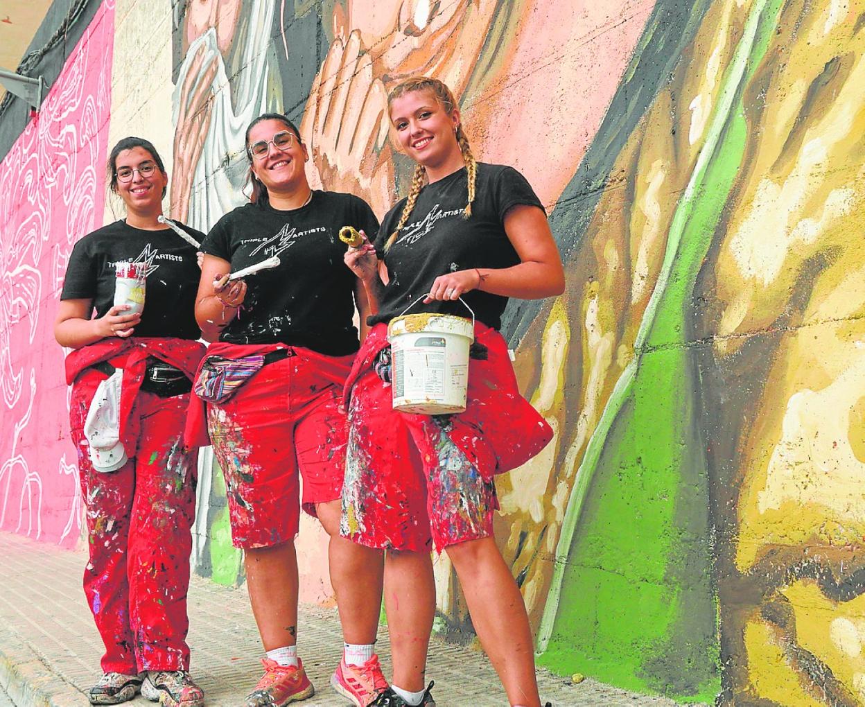María Fernández, María Escarabajal y María Soledad González-Reforma, durante el proceso creativo. Las tres artistas posan junto al mural terminado. 