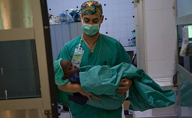 El anestesista Enrique Madrid conduce a un paciente a la zona de reanimación tras ser operado.
