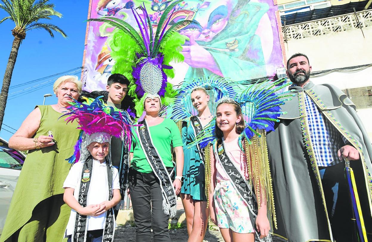 María Dolores Liebana, Fran Manchado, Fernando Hernández, Carmen María Nicolás, Silvia Marín, Rubí Pino y José Francisco Ruiz posan delante del mural del Carnaval que hay en Llano de Brujas. 