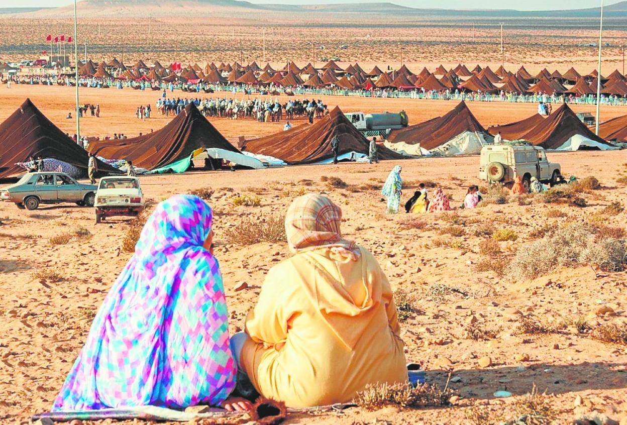 Dos mujeres observan la carrera de caballos en el Mussem (festival) de Tantán. En detalle, un camellero. 