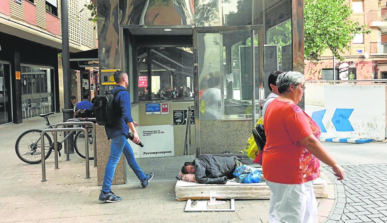 Una persona sin hogar, tumbada en un colchón junto a la entrada del parking subterráneo de la plaza Universidad. 