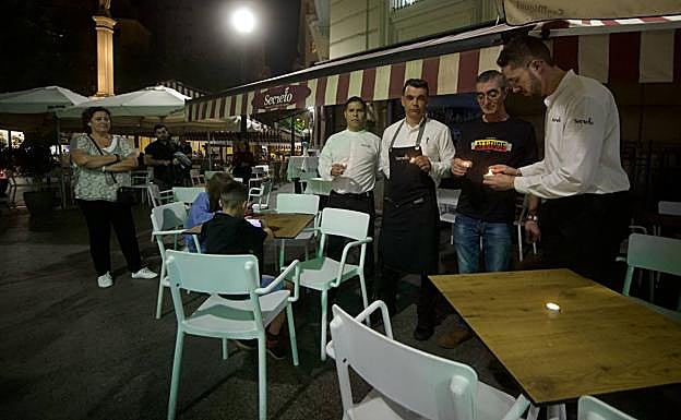 Camareros de un bar de la plaza de las Flores de Murcia colocan velas en las mesas durante el apagón simbólico de este martes.