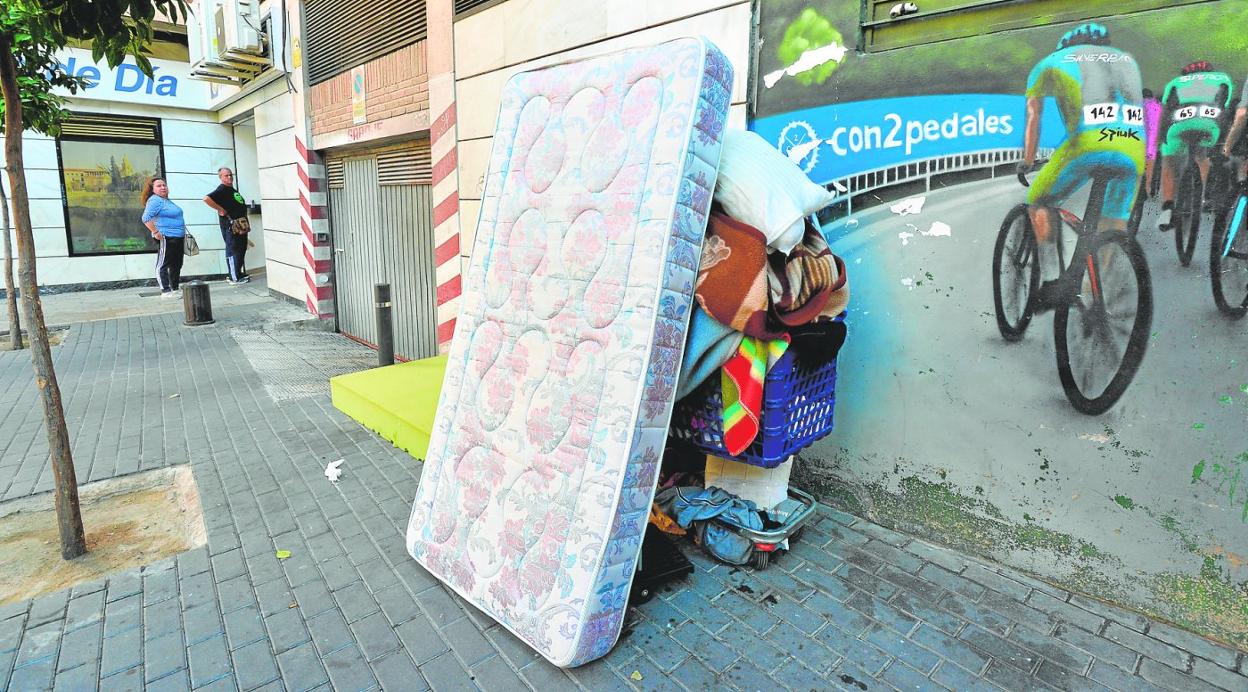 Varios colchones y mantas apoyados sobre un carro estacionado en la calle Baraundillo, usados para pernoctar en esta vía. 