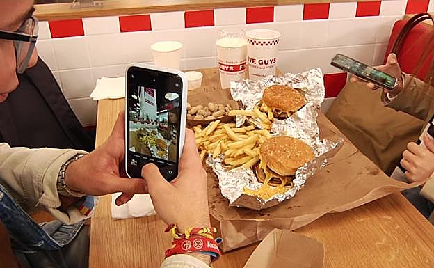 Clientes de Five Guys hacen una foto a su pedido en su primer día de apertura.