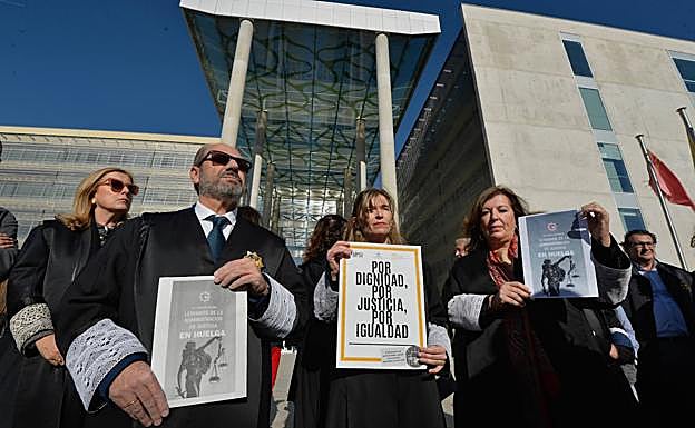 Letrados muestran carteles reivindicativos. 