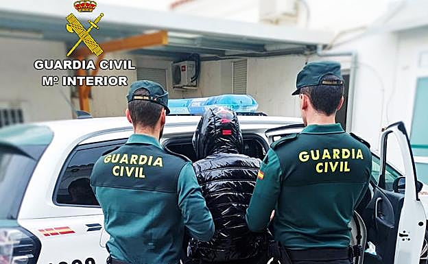 Dos agentes introducen al arrestado en un coche patrulla. 